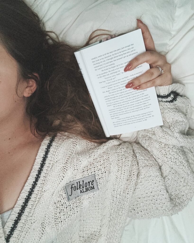 Woman laying on bed holding book